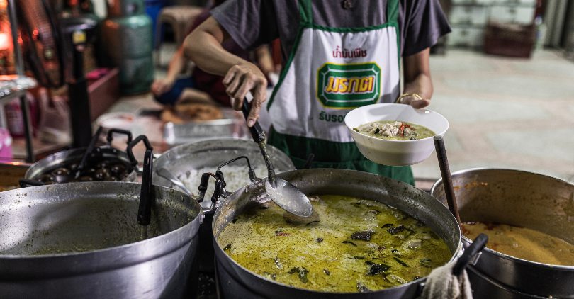 Women preparing a bowl of green curry