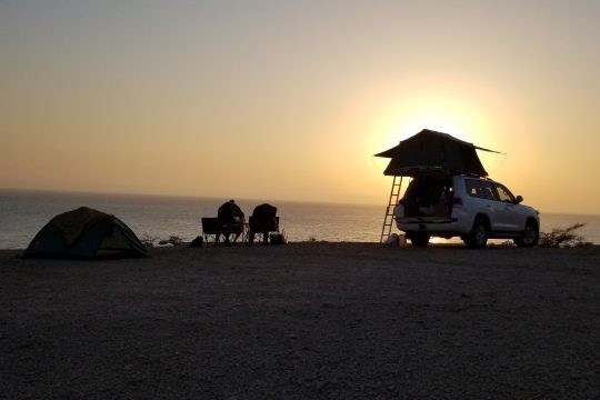 Couple camping in Oman beach with 4x4 rooftop tent